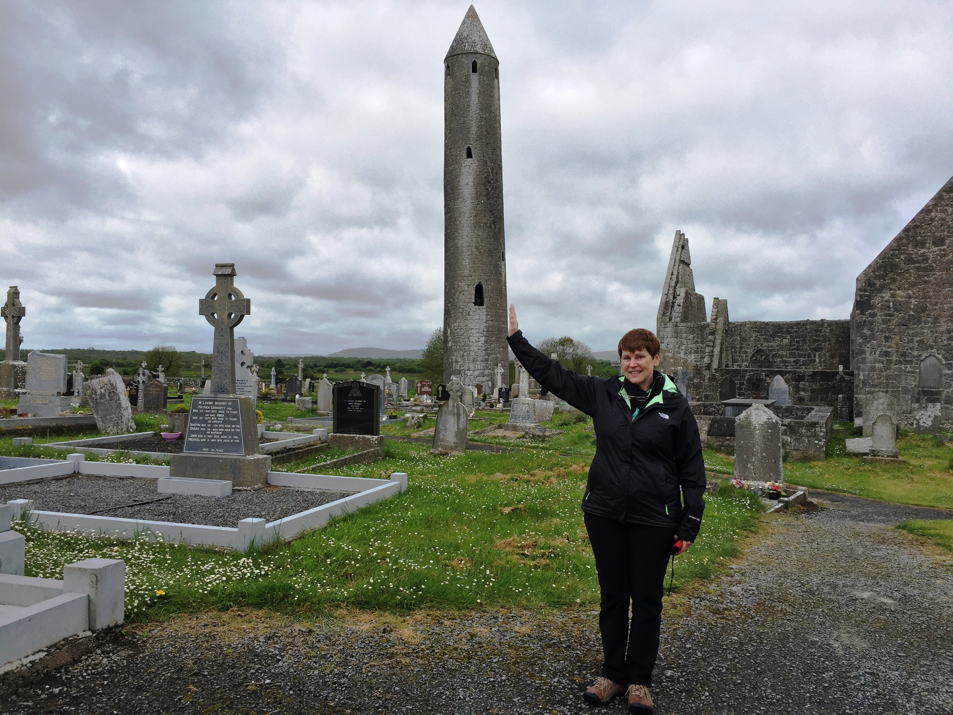 Molly reaches out a hand to steady the round tower at Kilmacduagh. Photo by Martha Clark.